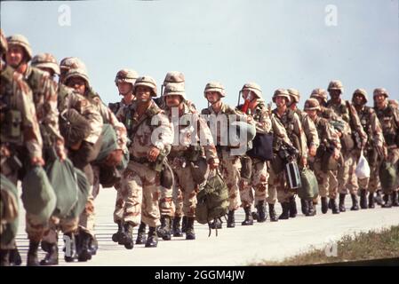 Fort Hood Texas USA, 1990: U.S. Army soldiers wearing desert-colored camouflage uniforms and carrying guns and gear prepare to board aircraft on their way to serve in the Middle East conflict. ©Bob Daemmrich Stock Photo