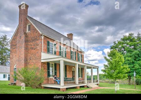 The Clover Hill Tavern with a civilian reenact sitting on its porch at the Appomattox Court House National Historical Park in Virginia. Stock Photo