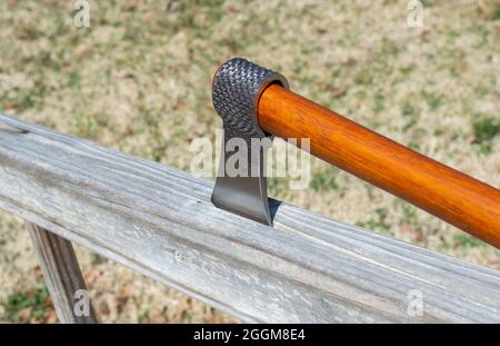 A tomahawk made from an old horseshoe rasp is on display using the wooden railing of an outdoor stairway. Bokeh effect. Stock Photo
