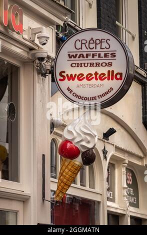 Amsterdam, Netherlands - August 14, 2021: Warmoesstraat. Closeup of sign for Sweetella chocolate and sweets store promoting crêpes, waffles, and every Stock Photo