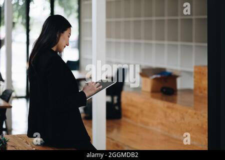 Asian attractive female professional drawing with stylus pen on digital tablet, business financial concept Stock Photo
