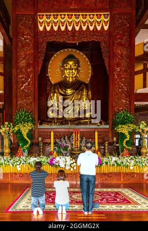 A Buddhist family is praying for peace in front of the main hall of an ancient temple on Buddha's birthday in Ho Chi Minh City, Vietnam Stock Photo