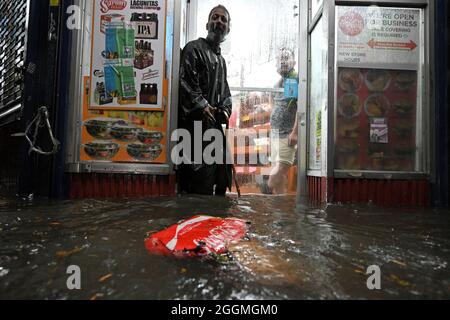 New York City, USA. 01st Sep, 2021. A homeless man stands in the doorway of a deli during flash flooding caused by storm Ida in the New York City borough of Queens, NY, September 1, 2021. (Photo by Anthony Behar/Sipa USA) Credit: Sipa USA/Alamy Live News Stock Photo