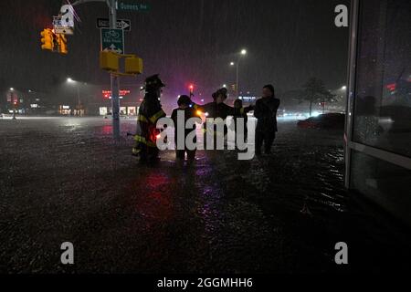 New York City, USA. 01st Sep, 2021. Members of the FDNY help people across Queens Boulevard through flash flood waters after remnants of Hurricane Ida brought three inches of rain per hour across the city, in the New York City borough of Queens, NY, September 1, 2021. (Photo by Anthony Behar/Sipa USA) Credit: Sipa USA/Alamy Live News Stock Photo