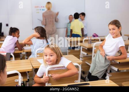 Cheerful preteen classmates talking at recess between lessons Stock Photo