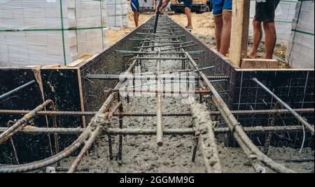 Pouring cement or concrete with automatic pump, construction site with reinforced grillage foundation, start of new house building construction. Stock Photo