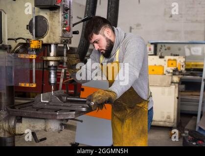 Man mechanic using drilling machine in workshop Stock Photo