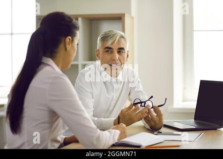 Senior businessman in the office discussing a new business project with his young female partner. Stock Photo