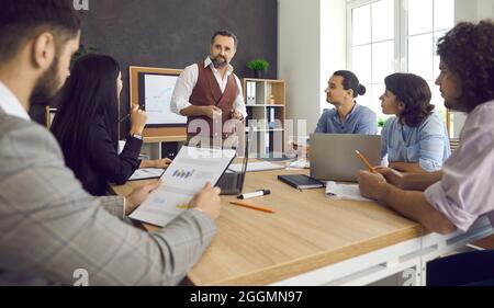 Group of people listening to a senior man while having a business meeting at work Stock Photo