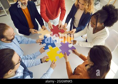 Business team joining puzzle parts as metaphor for teamwork and finding solution to problem Stock Photo