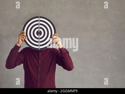 African american man holding dart board standing over grey studio background Stock Photo