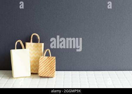 Brown paper shopping bags on white ceramic mosaic tile table. gray wall background Stock Photo