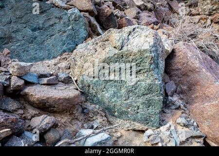 Raw ore of copper, green stones and rocks containing copper in old mining area, Hajar Mountains, United Arab Emirates. Stock Photo