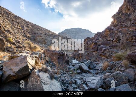 Stony, dry riverbed (wadi) with remains of raw ore of copper, green stones and rocks, Copper Hike Trail, Hatta, Hajar Mountains, UAE. Stock Photo