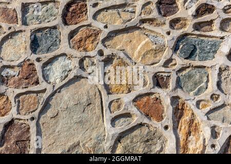 Colorful stony wall, multiple stones linked with cement, stone texture. Stock Photo