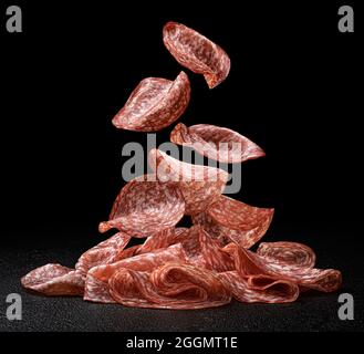 Falling salami slices isolated on black background Stock Photo