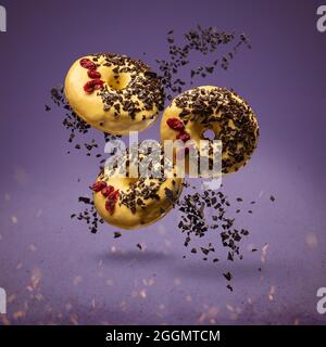 Flying donuts. Doughnuts with sprinkles on purple background Stock Photo