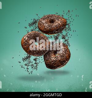 Sweet chocolate doughnuts in motion falling on green background. Stock Photo