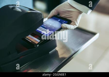 Scanning of boarding pass on mobile phone at airport counter. Cropped shot of airport staff hand scanning boarding pass on machine. Stock Photo