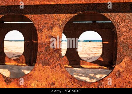 Rusty beams of the bridge located on the Baltic Sea, view of the beach on a sunny day Stock Photo