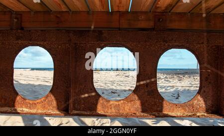 Rusty beams of the bridge located on the Baltic Sea, view of the beach on a sunny day Stock Photo