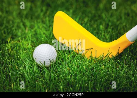 plastic toy golf ball and club on green grass Stock Photo