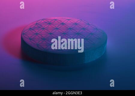 Round stone with carving under blue purple and red neon lights Stock Photo