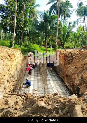 Construction in the jungle forest. Workers are pouring concrete into the foundation. Samui , Tailand - 02.26.2020 Stock Photo