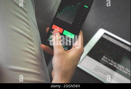 Trading stock market data and trading charts with mobile phone at home. Forex and brocker analysis concept Stock Photo