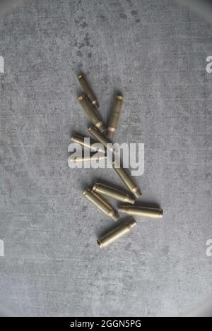 mix of brass used shell cases small calibre pistol bullets on grey concrete effect, background. Stock Photo