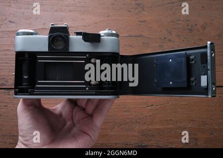 Old vintage 35 mm metal film camera, close-up. The panel of the film compartment is open. Stock Photo