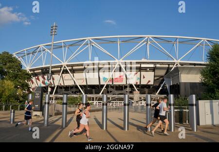 People joggin past the London Stadium by the Queen Elizabeth Olympic Park,London; England; UK Stock Photo