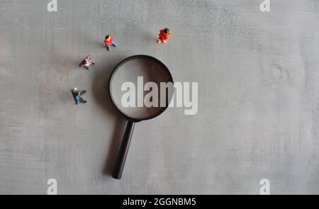 Concept of frequently asked questions, query, investigation, search for information. Miniature people looking at magnifying glass Stock Photo