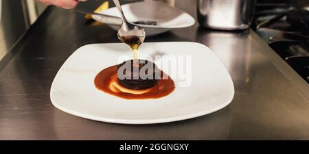 Chef putting the finishing touch on dessert plate while working in a restaurant kitchen. Cook concept. Stock Photo