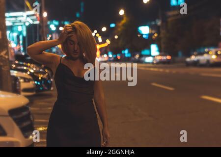 beautiful girl walks along the side of the road in the night city Stock Photo