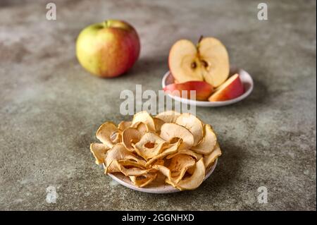 Dry apples chips, slices and apple fruit on rustic wooden background. Close up, selective focus Stock Photo