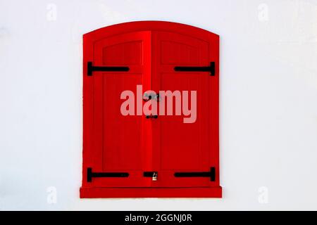 Red painted window shutters on a white coastal building Stock Photo