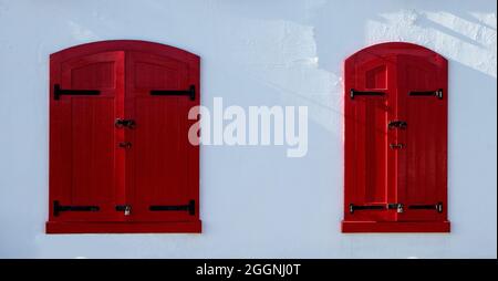 Red painted window shutters on a white painted building Stock Photo