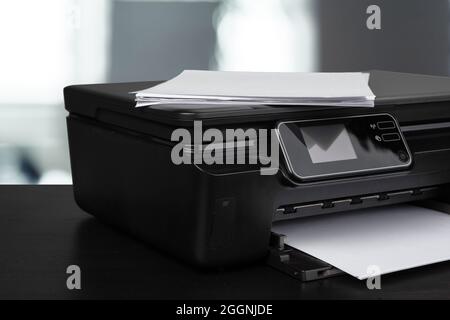 Compact laser printer on black desk against blurred background Stock Photo