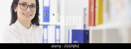 Young woman with glasses sitting at table in office Stock Photo