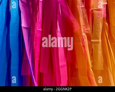 Colored silk ribbons hung in order to form a brightly colored gradient for use as a background decoration Stock Photo