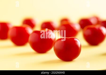 Pattern of red tomatoes on a light yellow background Stock Photo