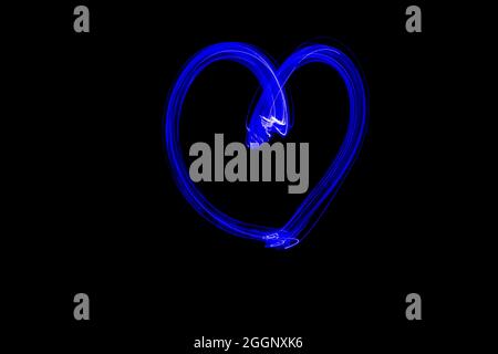 Light painting heart shape. Drawn heart with blue neon lights. Long exposure photography. Isolated on black. February 14 Valentine's day background. Stock Photo