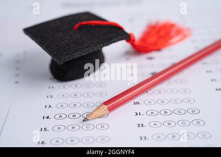 Graduation gap hat and pencil on answer sheet background, Education study testing learning teach concept. Stock Photo