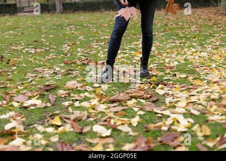 woman's legs in park with autumn leaves Stock Photo