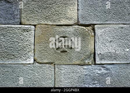 Close up of a gray stony bricked wall with small sculptured cross inside a stone Stock Photo