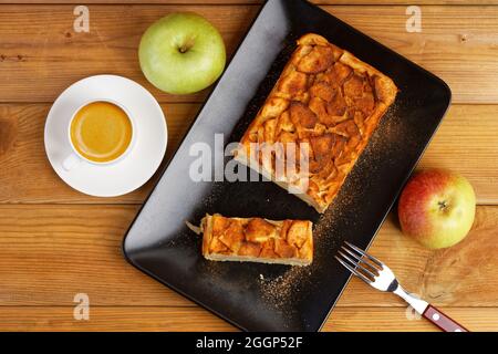 French apple cake. Homemade apple clafouti and cup of coffee espresso on wooden table. Top view. Stock Photo