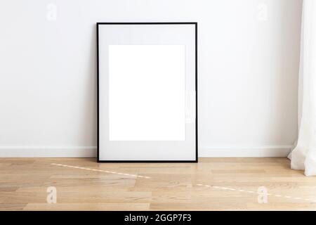 Rectangular mock up frame with passepartou standing in a room with wooden flooring. Stock Photo