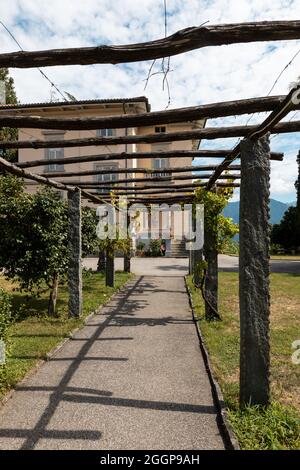 Ancient villa entrance with stone porch and wooden logs. Nobody inside. Sunny summer day Stock Photo