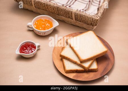 Toast with strawberry and orange jam on a plate on table. Stock Photo